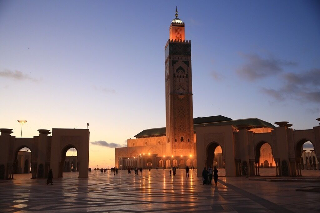 A large mosque with a tall minaret, arched walkways, and a spacious courtyard.