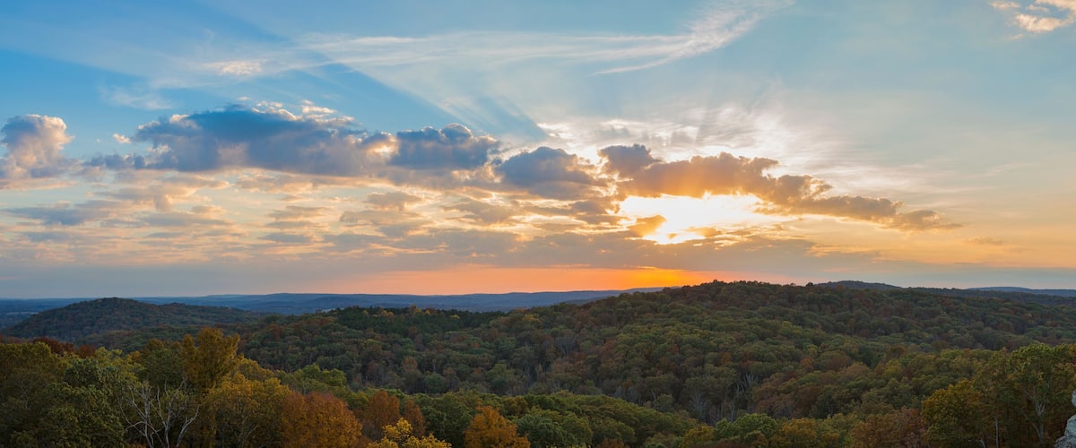 A forested mountain range with a sunset.