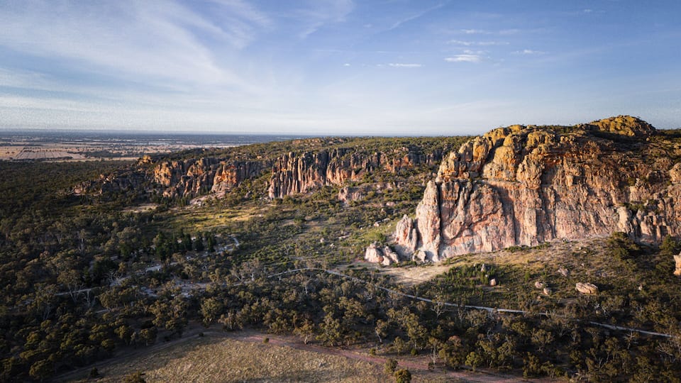 A rugged landscape with prominent rock formations and a dense forested area.