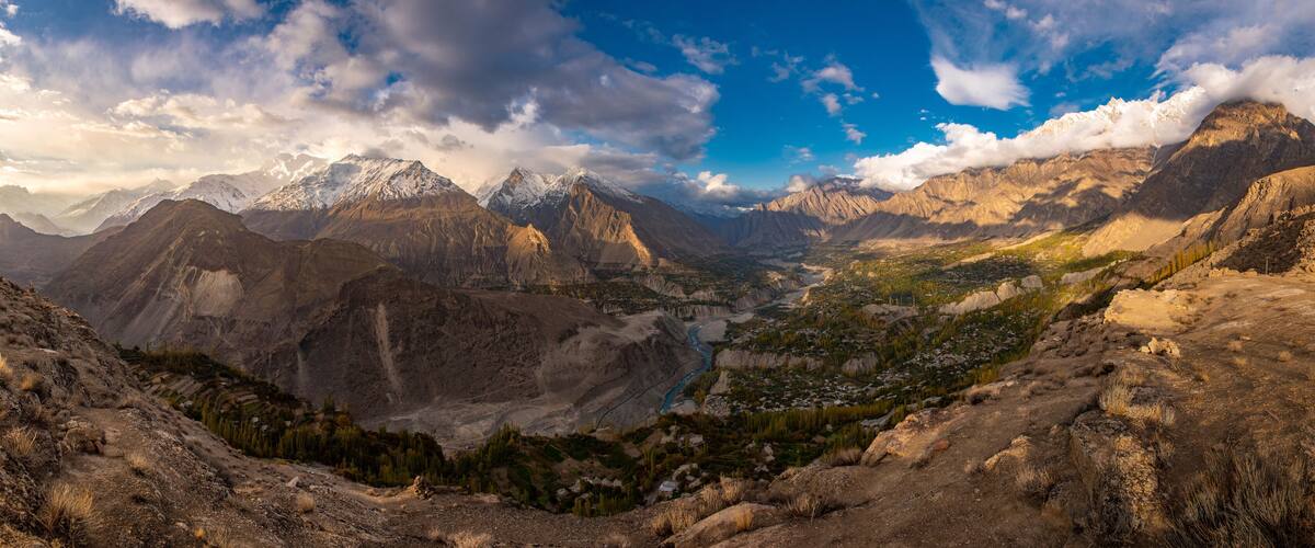 A mountainous landscape with snow-capped peaks, a winding river, and a valley with sparse vegetation.