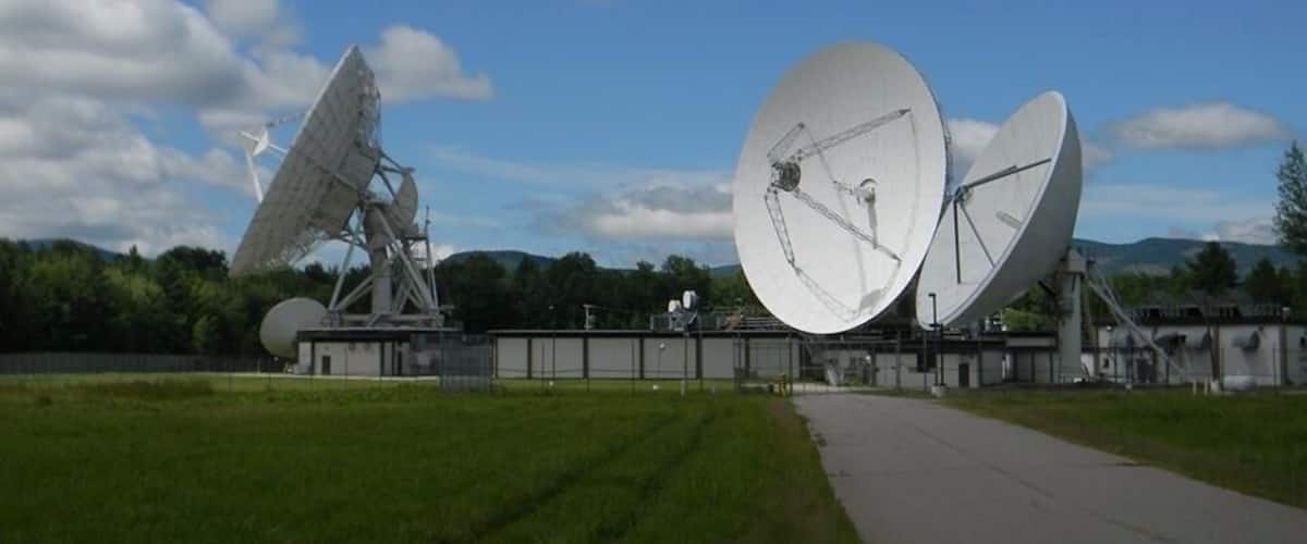 Large satellite dishes in an open field with a clear sky.