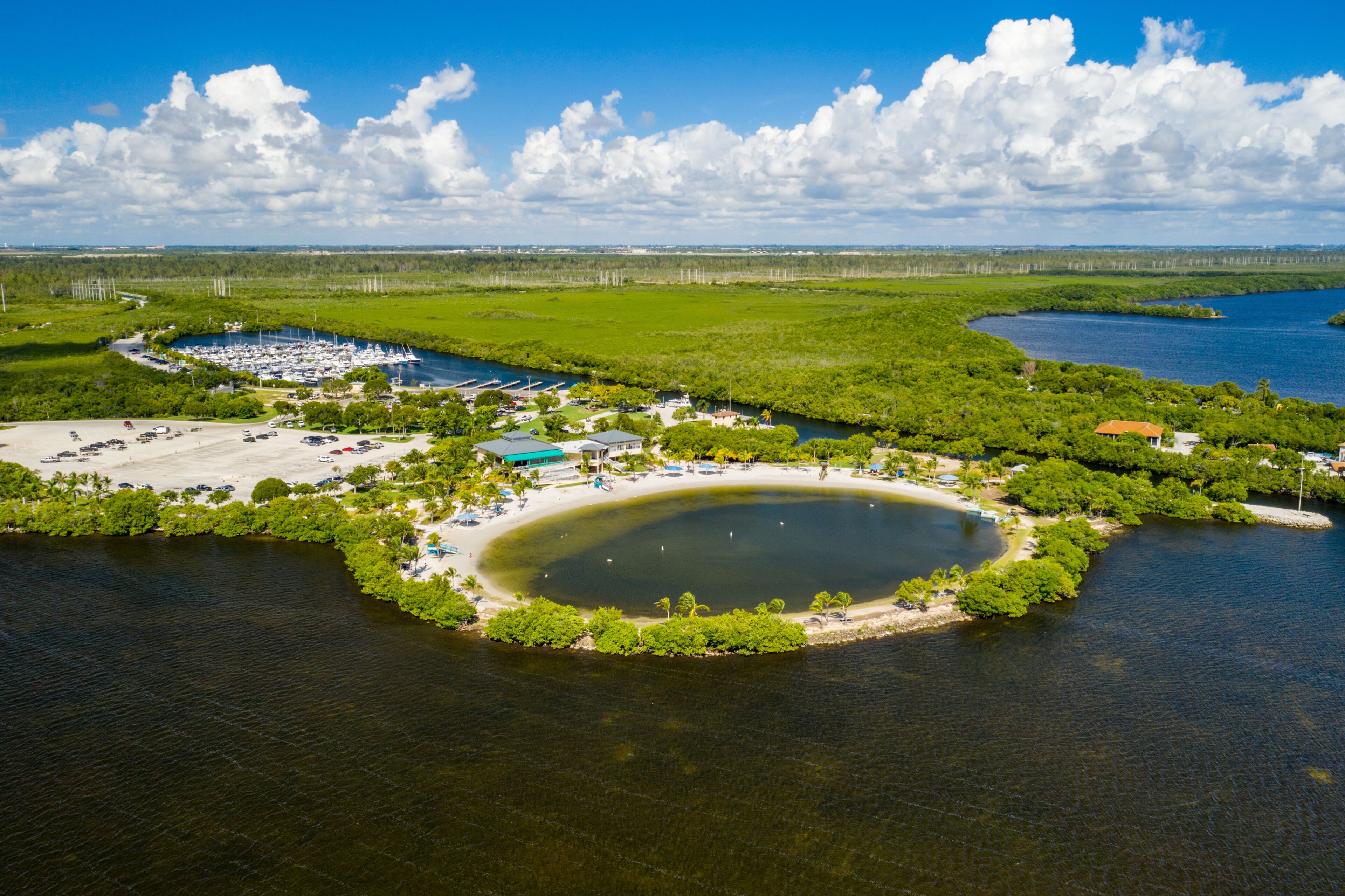 Zona costera con un puerto deportivo, una playa de arena y una extensa masa de agua.