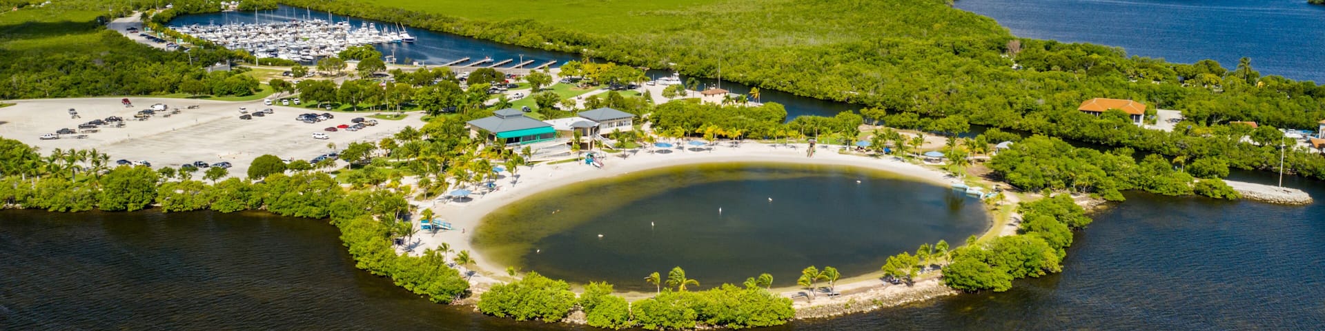 A coastal area with a marina, a sandy beach, and a large body of water.