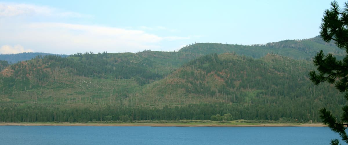 A calm lake surrounded by forested hills.