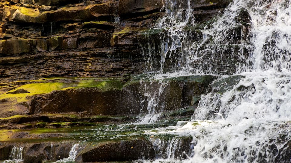 A cascading waterfall over rocky terrain with moss-covered stones.