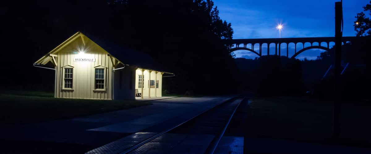 A train station at night with a bridge in the background.