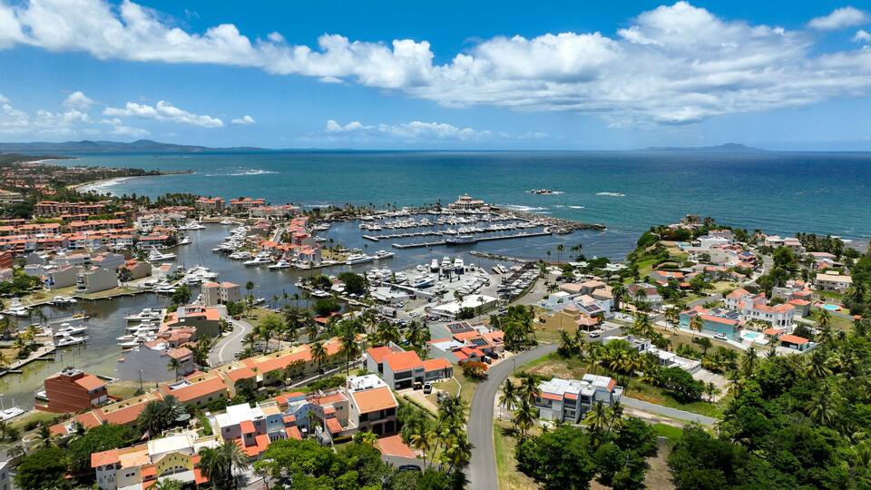 A coastal town with a marina, houses, and a clear blue sky.