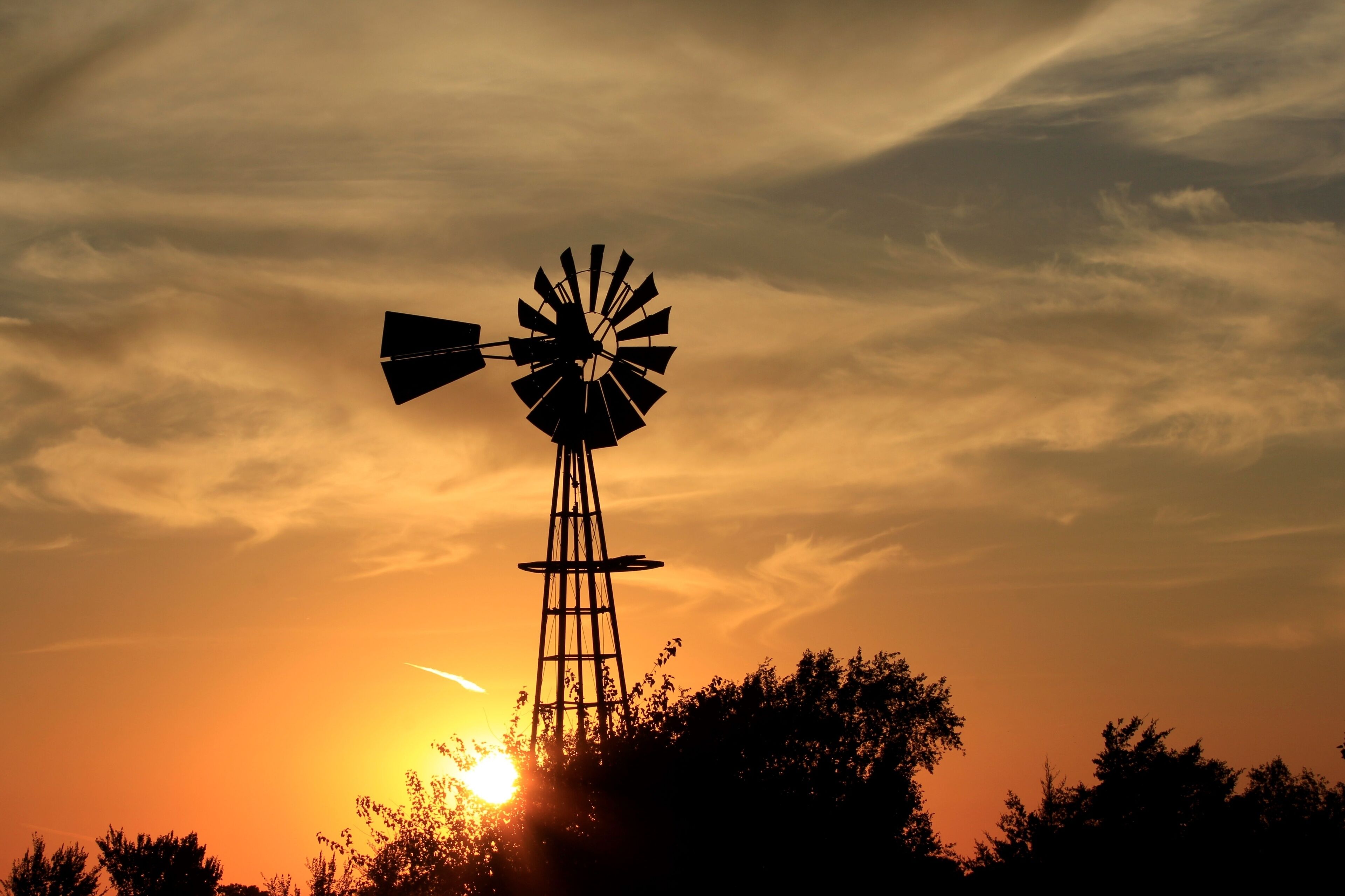 Kansas Sunset with a colorful sky and clouds with a Windmill silhouette north of Hutchinson Kansas USA.