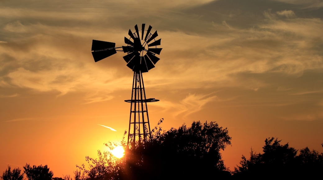 Kansas Sunset with a colorful sky and clouds with a Windmill silhouette north of Hutchinson Kansas USA.