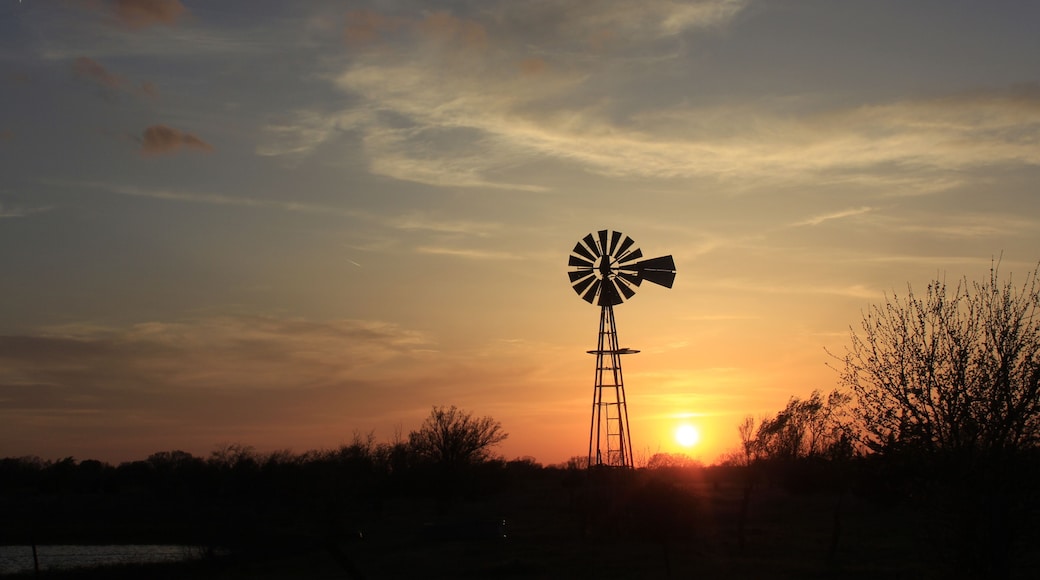 windmill at sunset with colorful clouds north of Hutchinson Kansas USA out in the country.