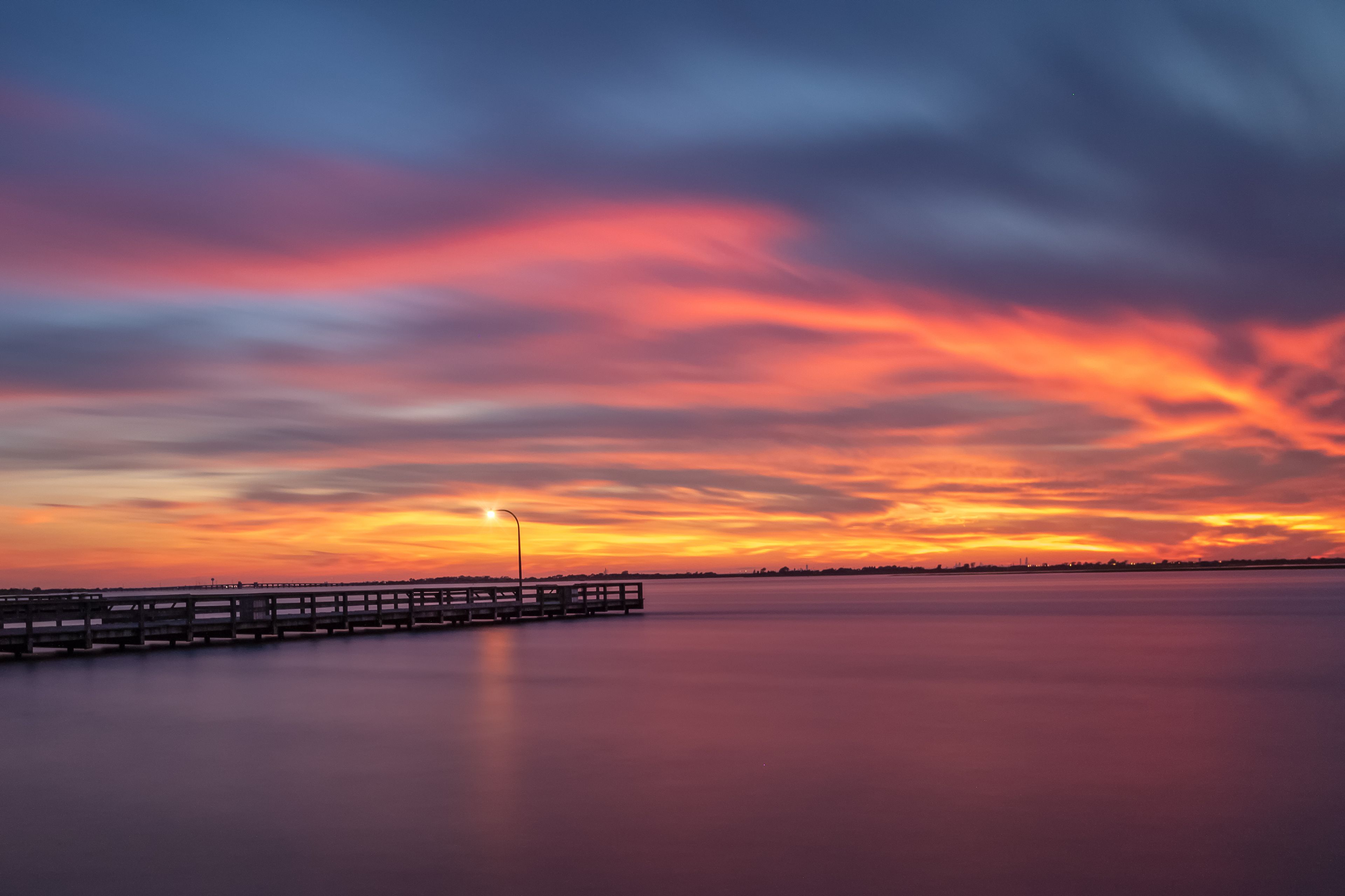Vibrant colors light up the sky just after sunset over a long fishing pier. Jones Beach, Long Island New York