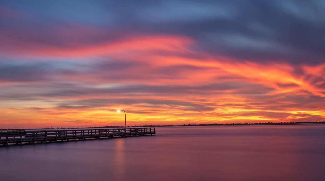 Vibrant colors light up the sky just after sunset over a long fishing pier. Jones Beach, Long Island New York