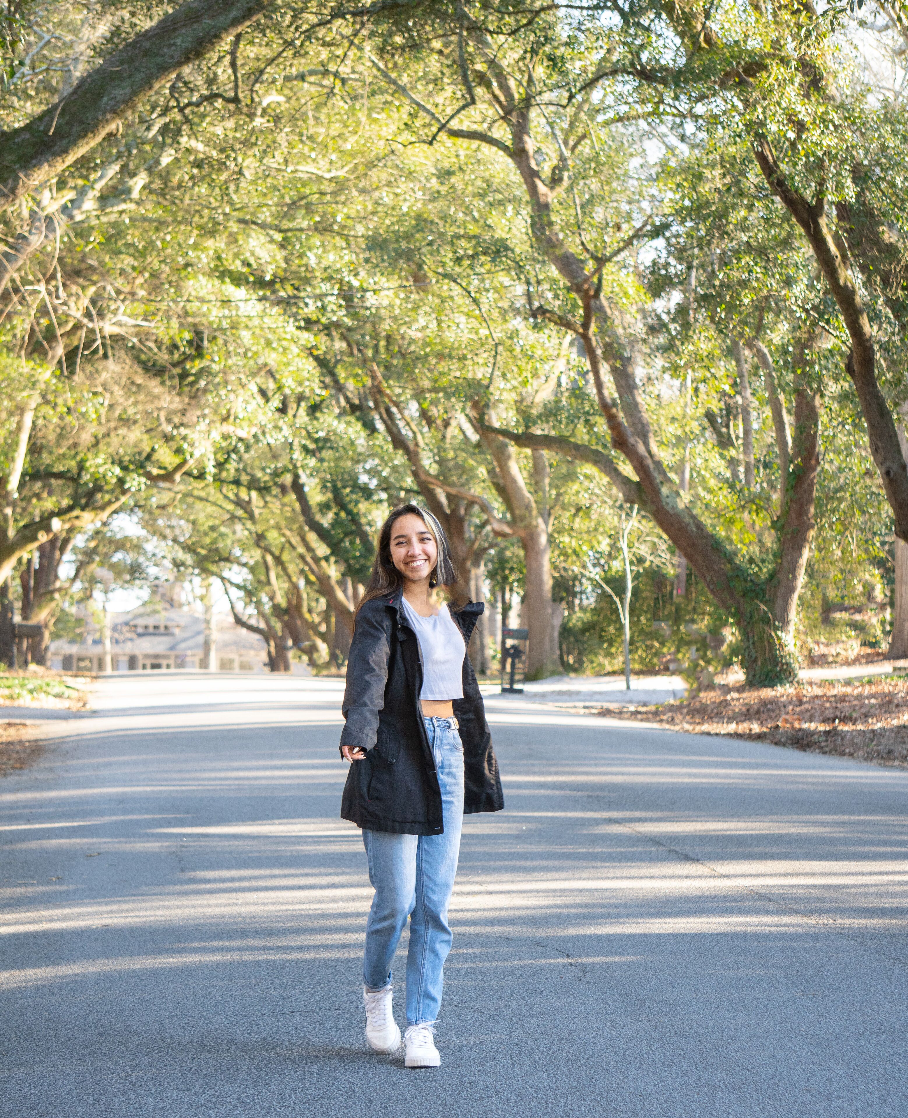 Young Woman Walking Down the Street in a tunnel of Trees