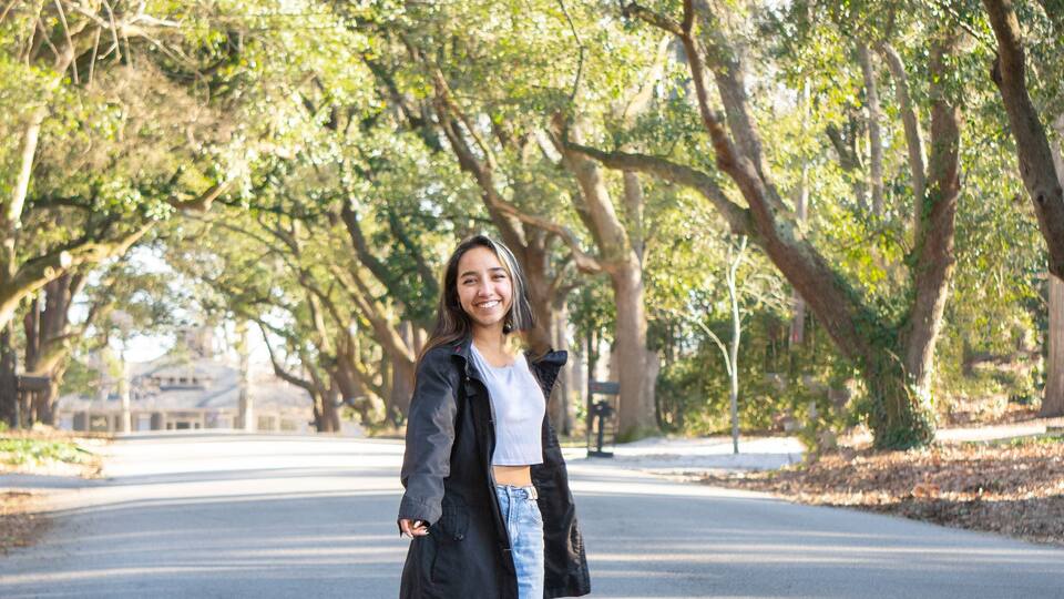 Young Woman Walking Down the Street in a tunnel of Trees