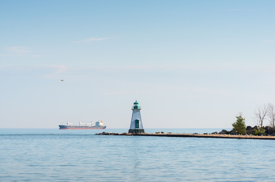 Un faro en un muelle con un carguero al fondo.