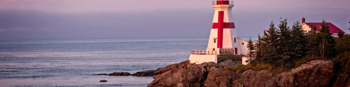 A lighthouse on a rocky coast with the ocean in the background.