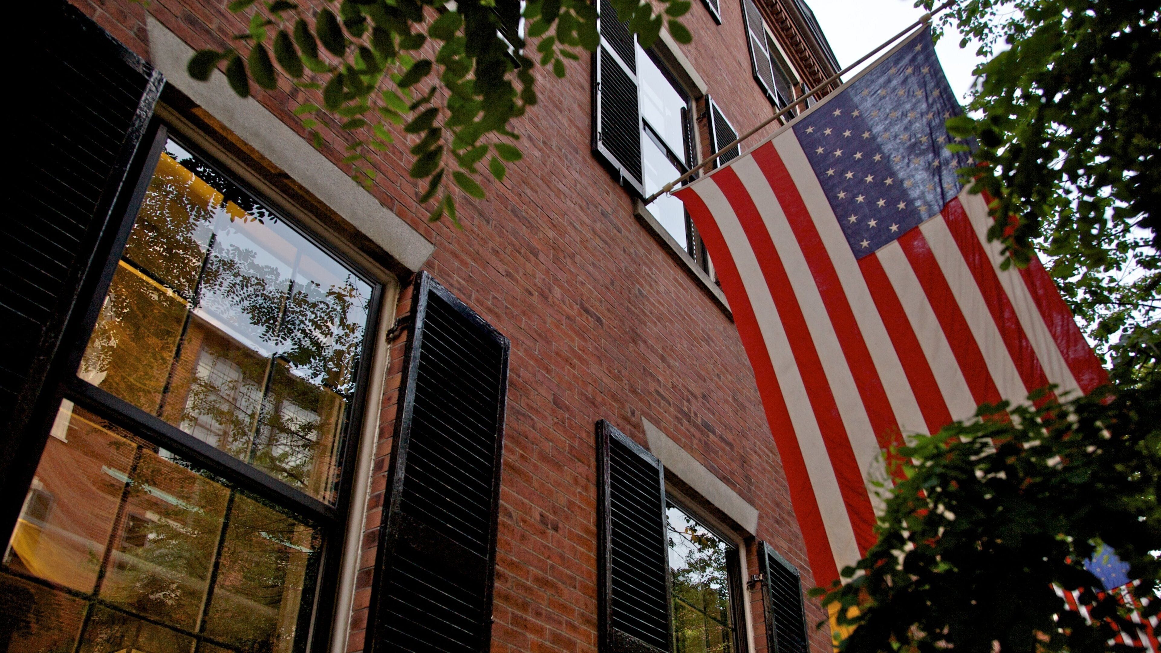 Vibrant American flag hangs outside historic building in Beacon Hill, Boston, showcasing architectural charm