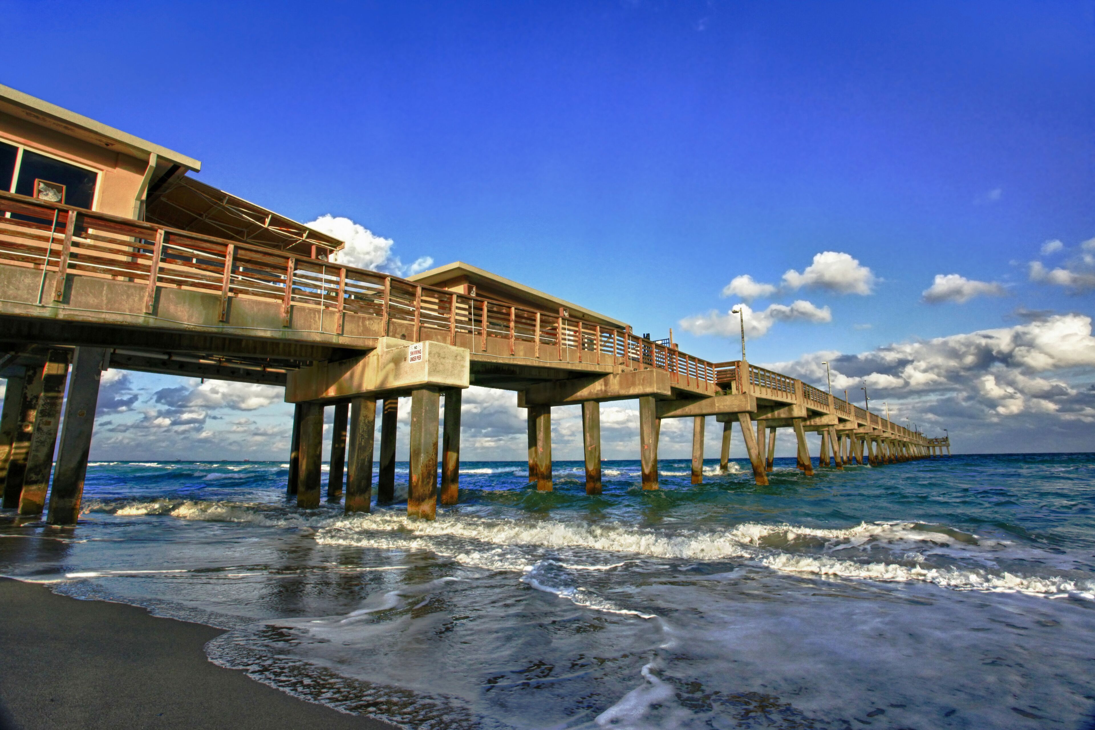 A pier extending into the ocean with waves crashing against it.