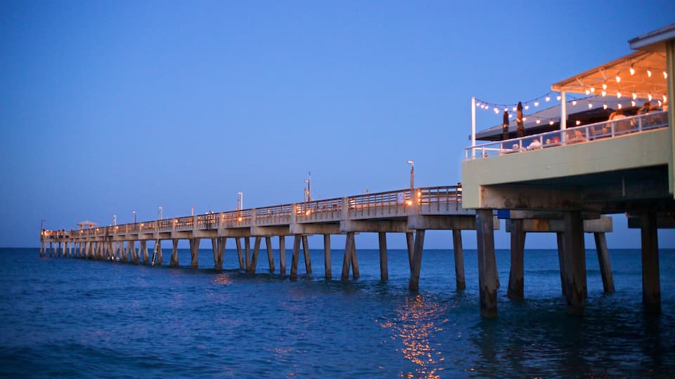 A pier extending into the water with lights and a covered area on the right.