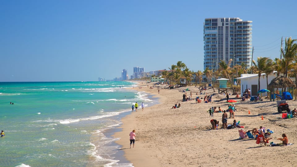 A beach with clear turquoise water, people sunbathing, and palm trees.