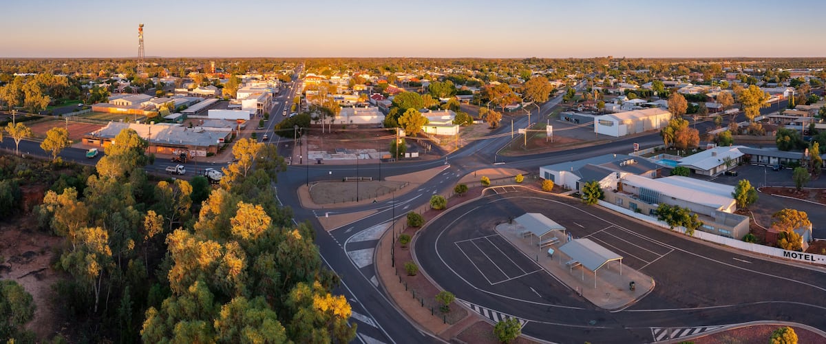 An aerial view of a town with a central roundabout, a motel, and surrounding residential and commercial buildings.
