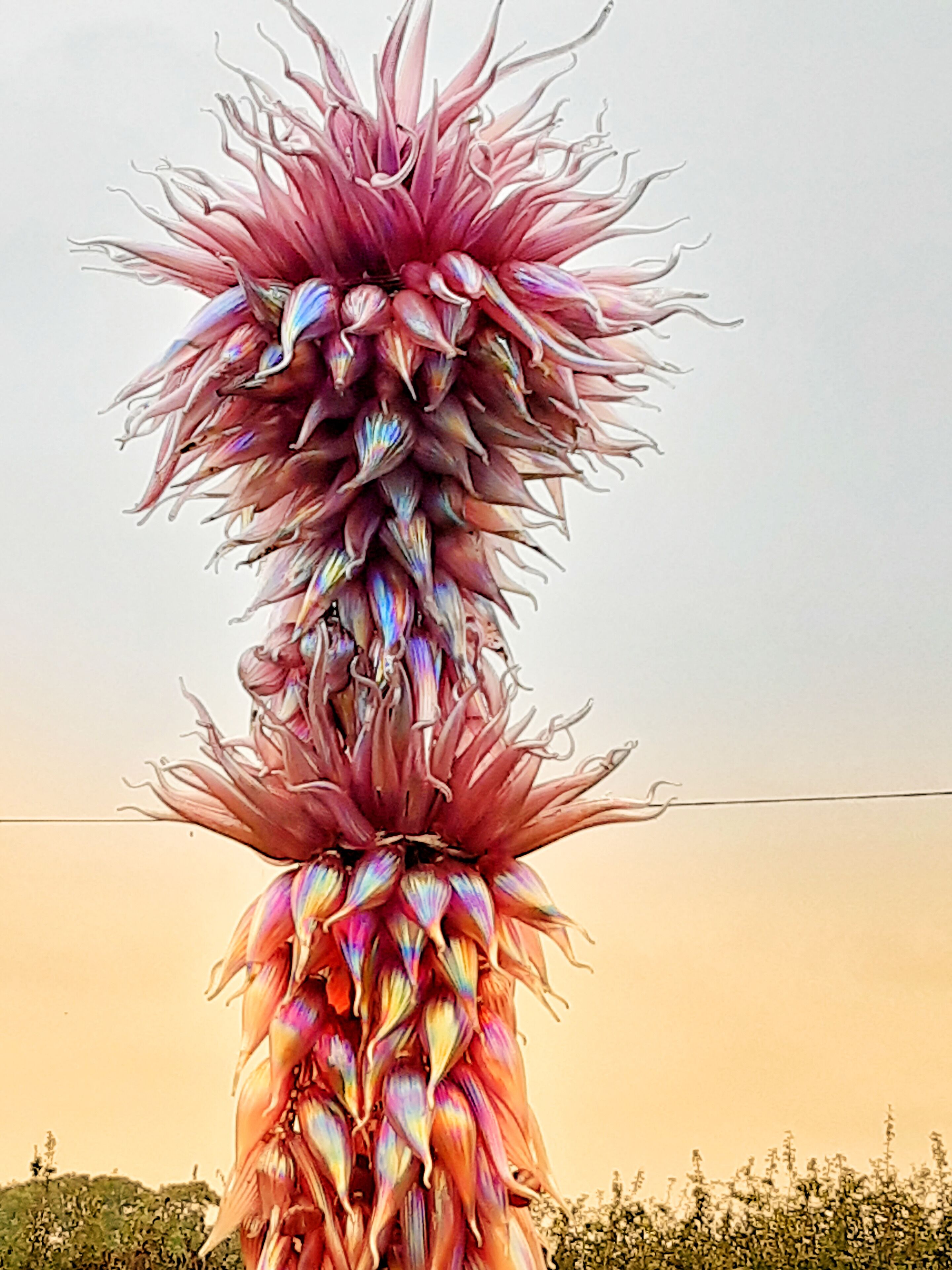 A tall, colorful flower sculpture against a clear sky.