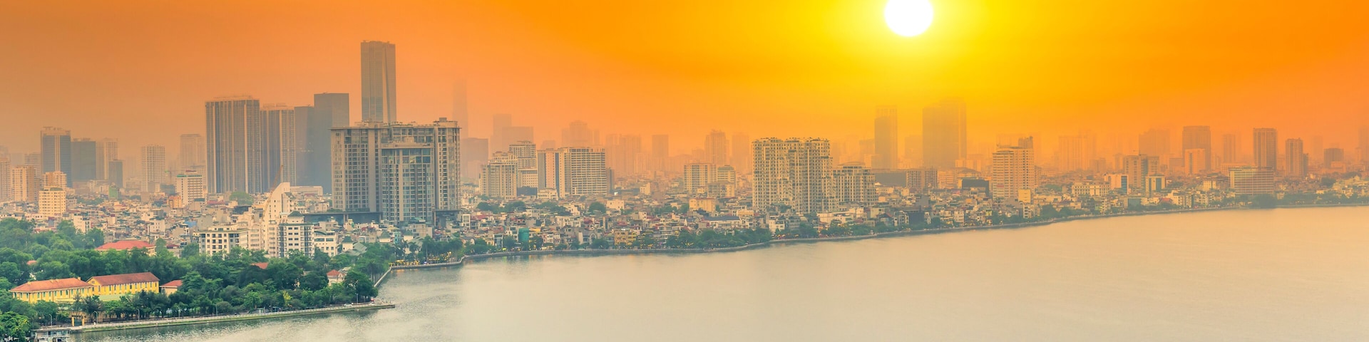Aerial view of road crossing the island Westlake, Hanoi, Vietnam with green tree lined street, temple located between small oasis. A beautiful sunset in capital of Vietnam