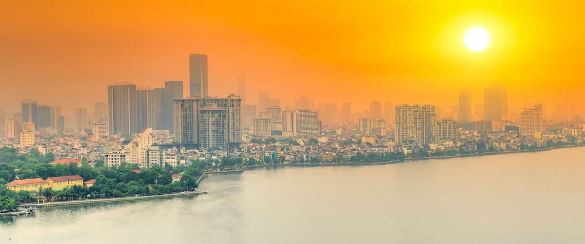 Aerial view of road crossing the island Westlake, Hanoi, Vietnam with green tree lined street, temple located between small oasis. A beautiful sunset in capital of Vietnam