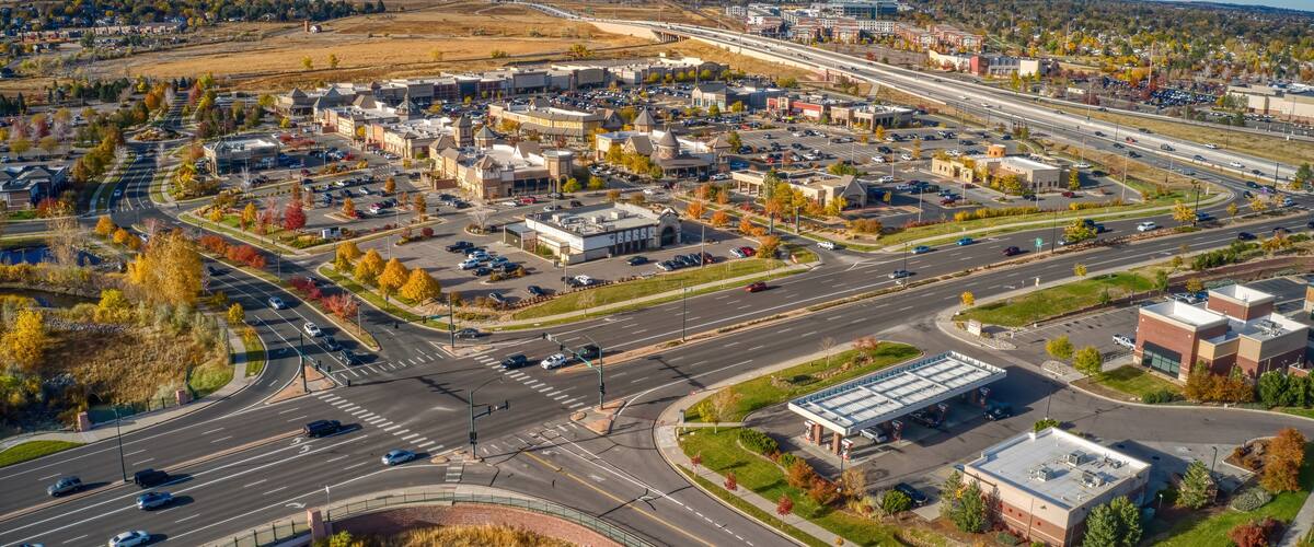 An aerial view of a city with a highway, buildings, and autumn foliage.