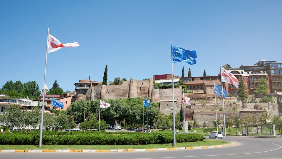 A roundabout with flags, a historic building, and modern architecture.