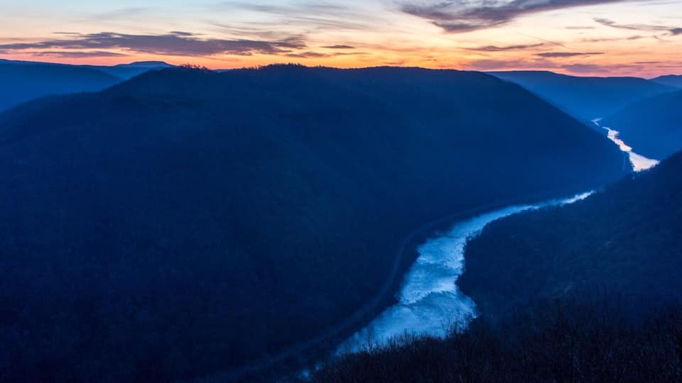A river winding through a mountainous landscape at dusk.