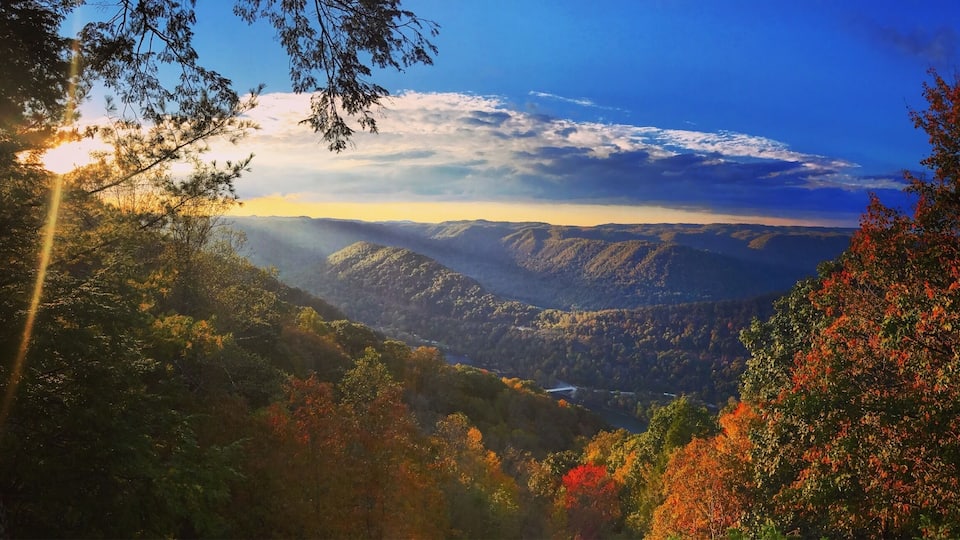 A mountainous landscape with autumn foliage and a river valley.