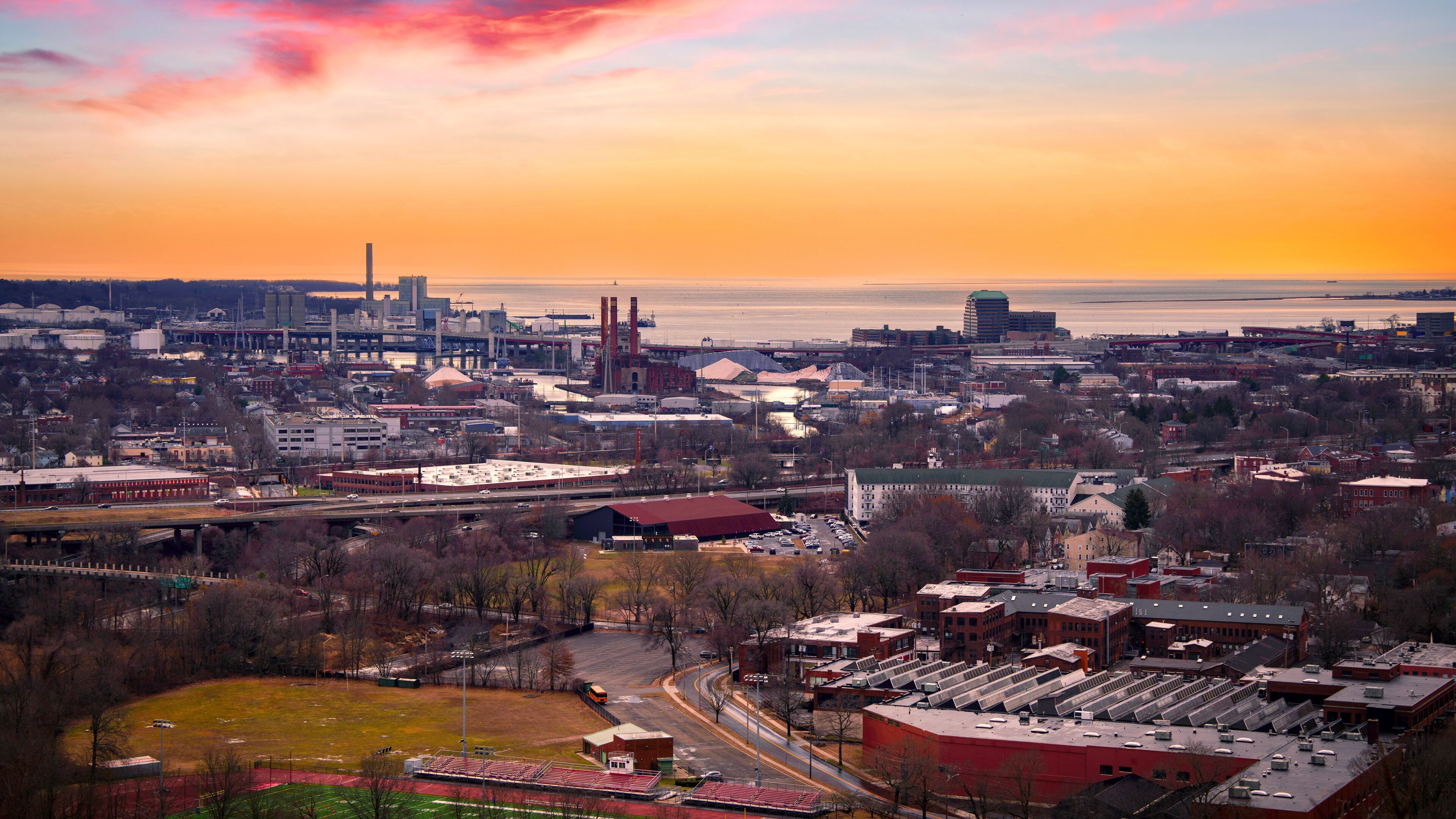 A cityscape with a river, industrial buildings, and a stadium.