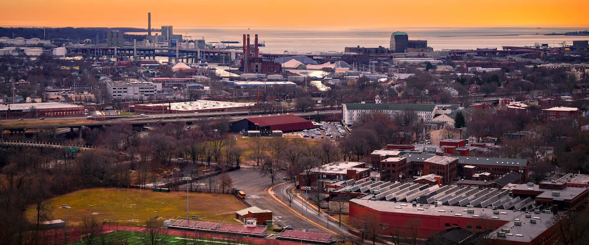 A cityscape with a river, industrial buildings, and a stadium.