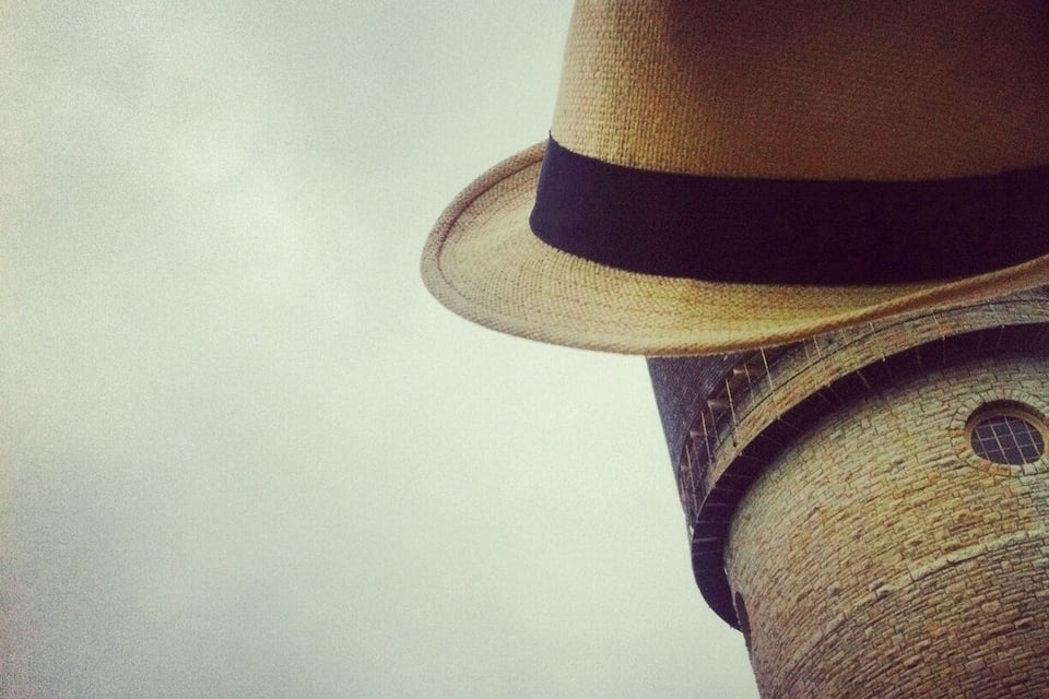 A straw hat with a black band on a stone tower.