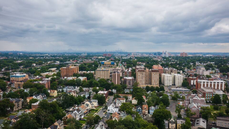 A cityscape with dense urban buildings, a mix of residential and commercial structures, and a distant skyline.