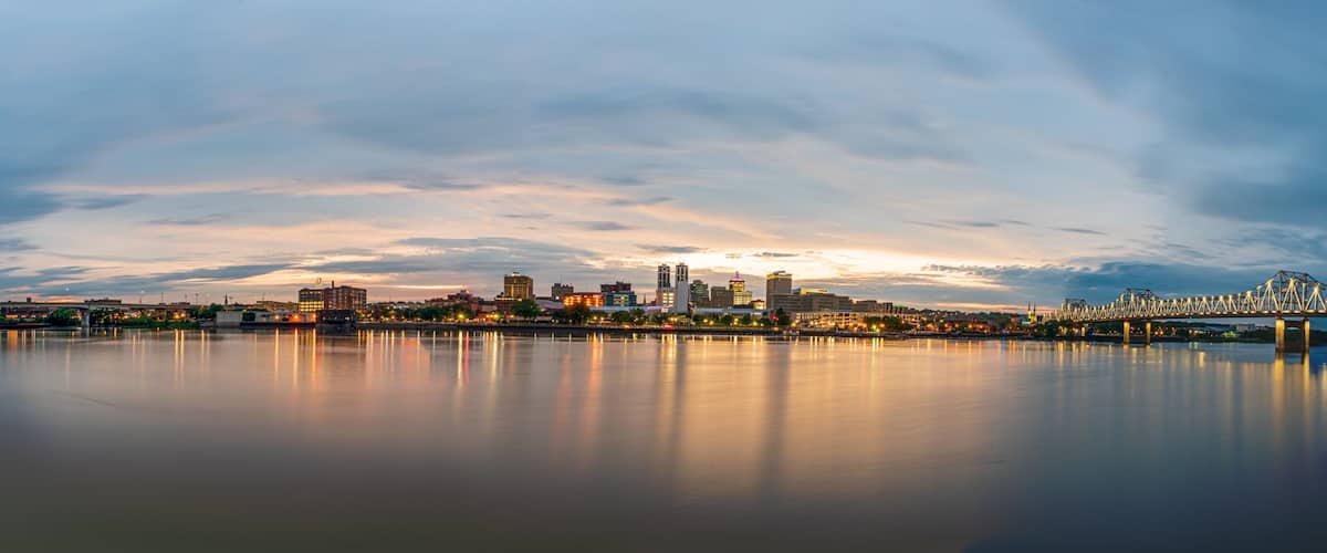 A city skyline with a prominent bridge spanning a calm river, reflecting the city lights.