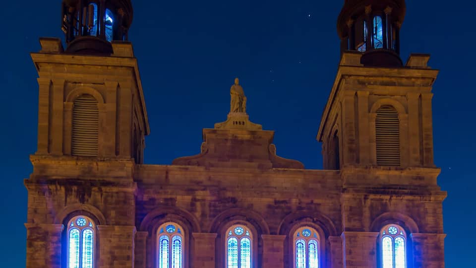 A historic building with two towers and illuminated windows at night.