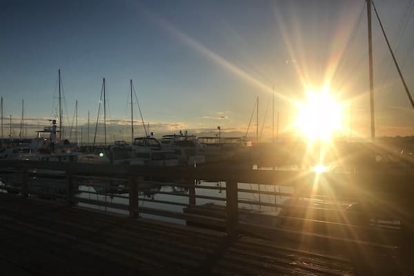 Ein Hafenbecken mit vertäuten Booten bei Sonnenuntergang.