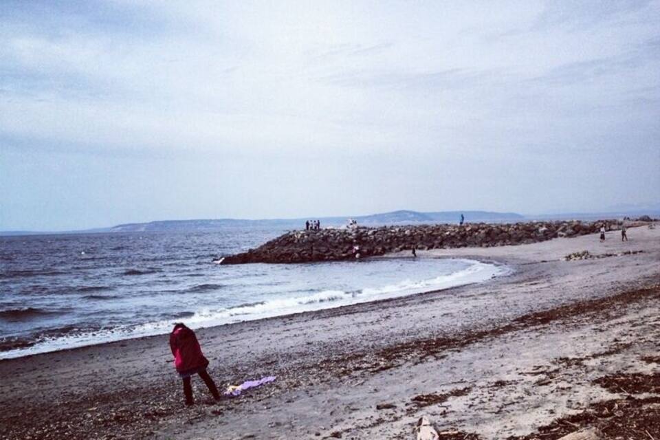 Una playa con un afloramiento rocoso y olas rompiendo sobre la orilla.