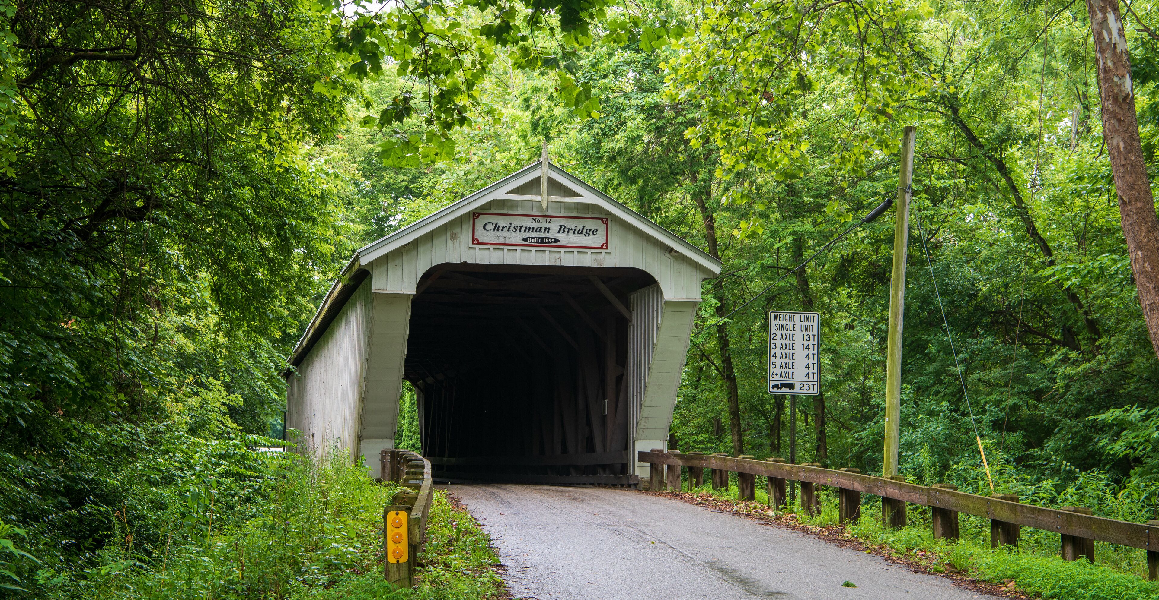 A covered bridge named 'Christman Bridge' with a sign indicating weight limits for vehicles.