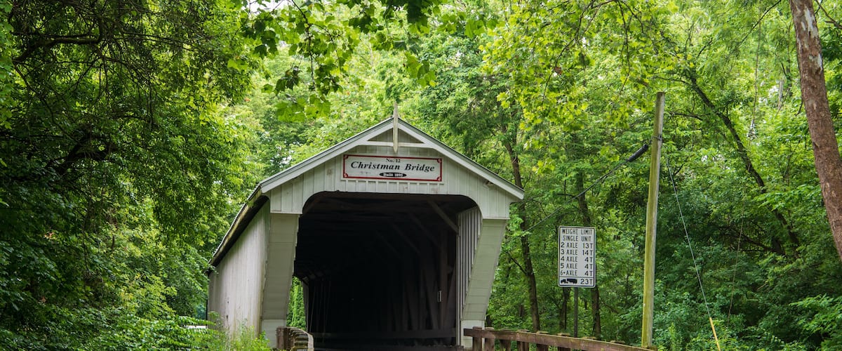 A covered bridge named 'Christman Bridge' with a sign indicating weight limits for vehicles.