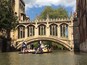 A historic stone bridge with arched windows and intricate carvings, spanning a river with people in boats.