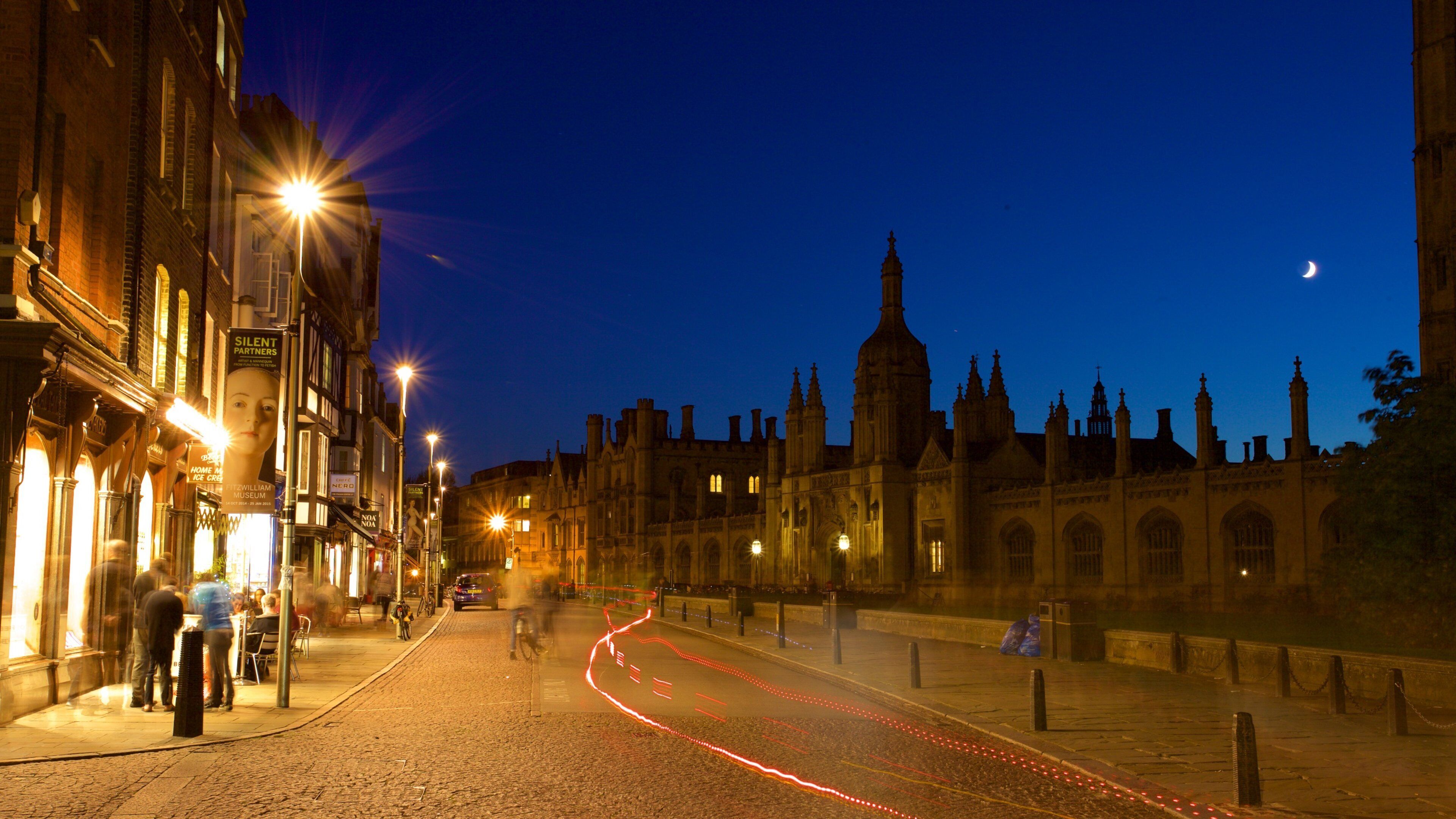 A historic building with Gothic architecture, a cobblestone street, and illuminated signs.