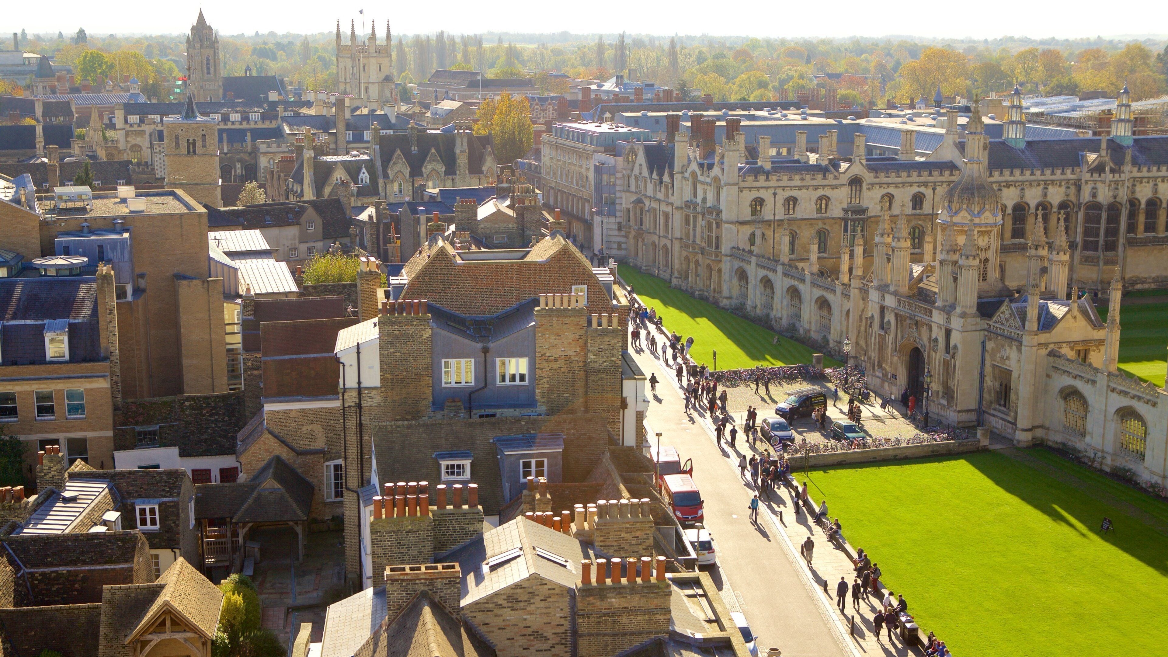 A historic university campus with a prominent clock tower, a large lawn, and a mix of traditional and modern buildings.