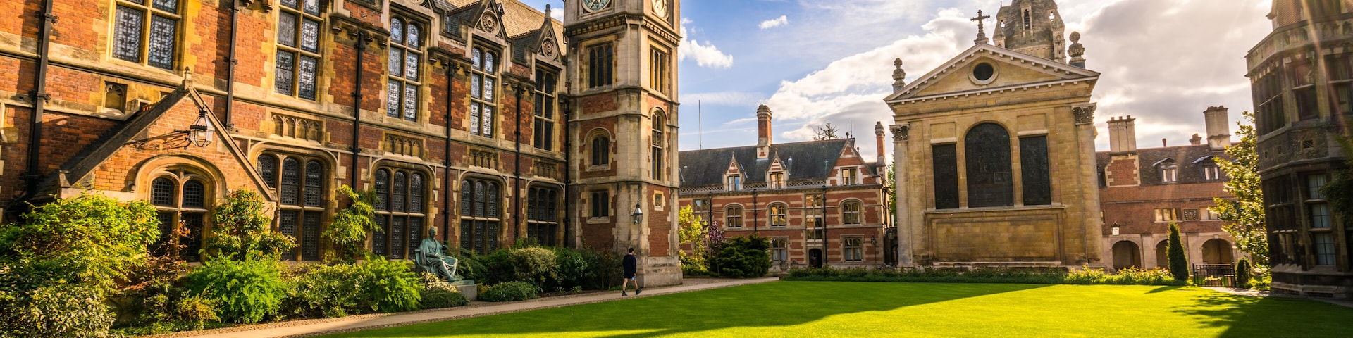 A historic university campus with red brick buildings, a central lawn, and a prominent clock tower.