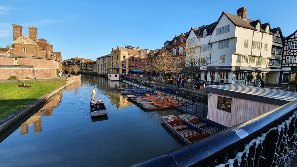 A canal with boats, historic buildings, and a castle in the background.