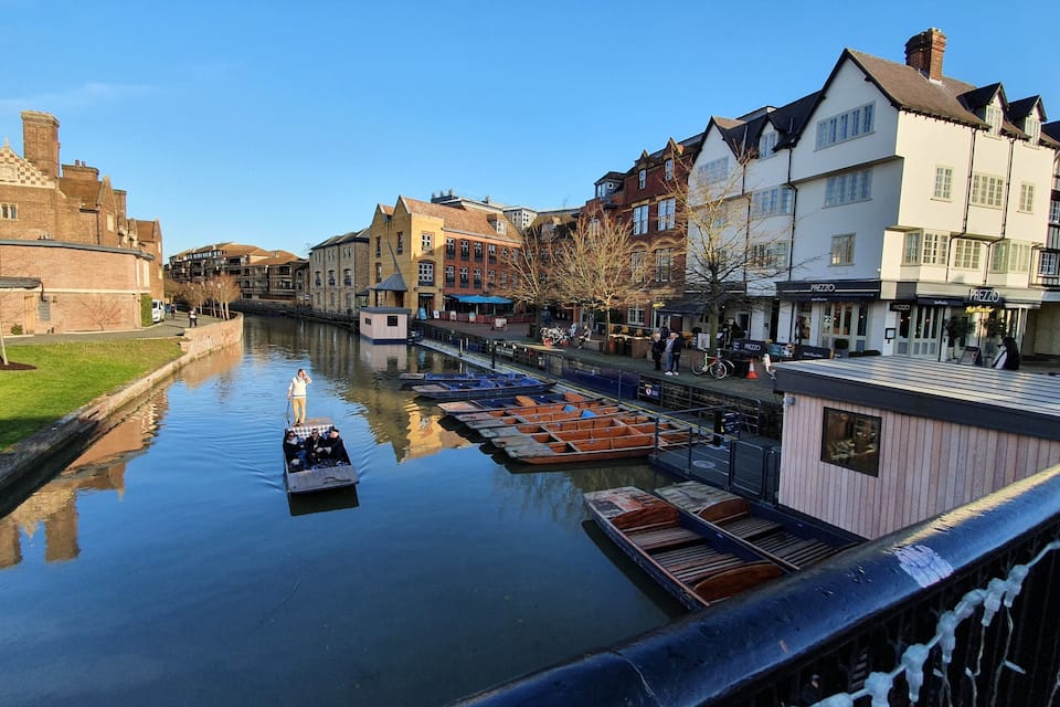 A canal with boats, historic buildings, and a castle in the background.