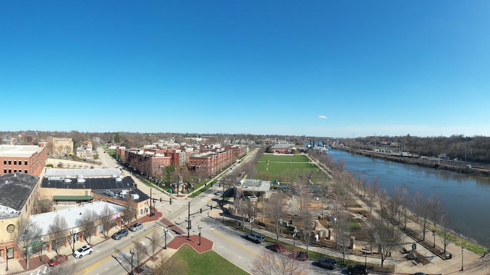 A river with a bridge, a park, and buildings along the riverbank.