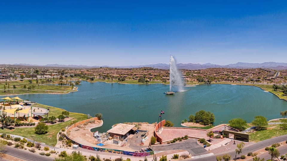 A large lake with a central fountain, surrounded by residential areas and mountains in the background.